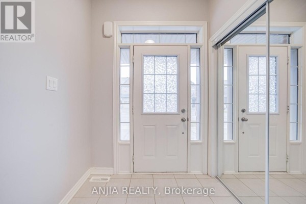 Interior view of a hallway with a white front door, sidelight windows, and a mirrored closet door. - 115 Wilfred Murison Avenue, Markham