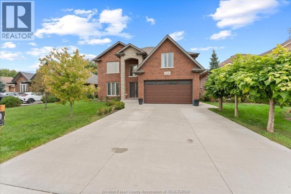 Wide shot of the front of a residential house with a long concrete driveway and green lawn. - 1150 Jillian Court, Lakeshore