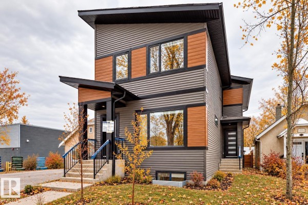 Exterior of a modern house with brown and grey siding, multiple windows, and a covered porch. - 11519 & 11521 67 St Nw, Edmonton