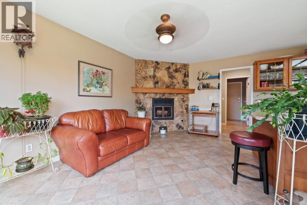 Another angle of the living room showcasing a stone fireplace and seating area. - 11523 Bonson Road, Pitt Meadows