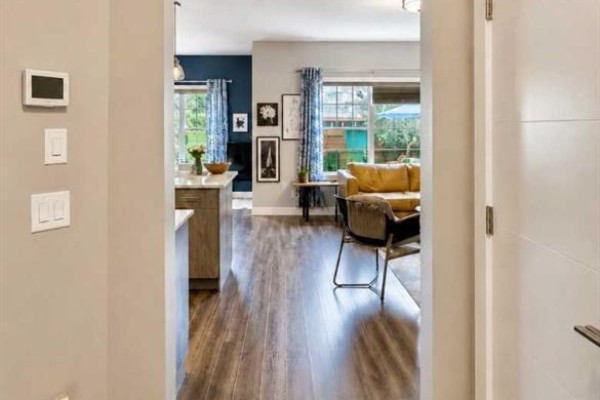 Entrance foyer with white door, wood railing, windows, and wall art. - 1155 Kings Heights Way Se, Airdrie