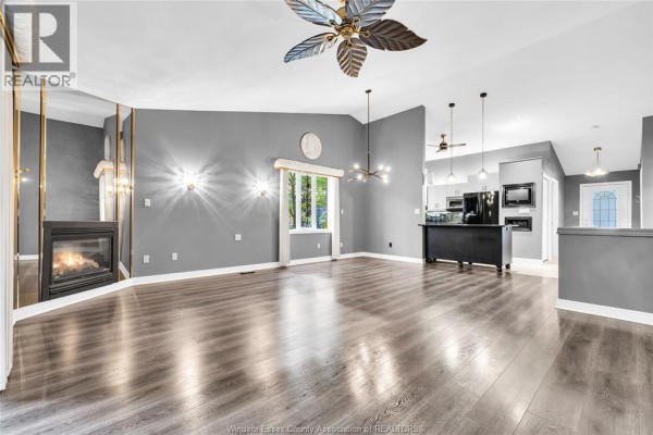 Living room with a fireplace, large windows, and laminate flooring. - 11568 Aldridge, Windsor