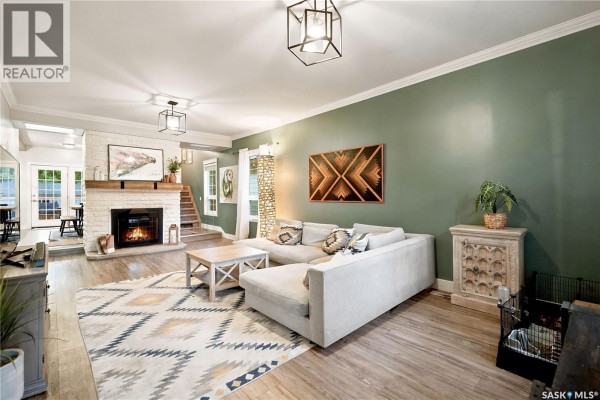 Living room with a sectional sofa, fireplace, wooden mantel, and a large geometric rug. - 1157 3rd Avenue Nw, Moose Jaw