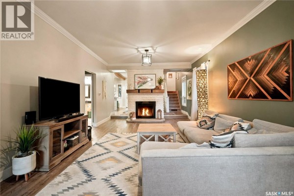 Living room featuring a TV, fireplace, sectional sofa, and decorative wall art. - 1157 3rd Avenue Nw, Moose Jaw