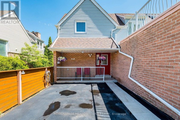 Front porch area with red chairs, brick wall, and attached garage. - 1157 Kos Boulevard, Mississauga