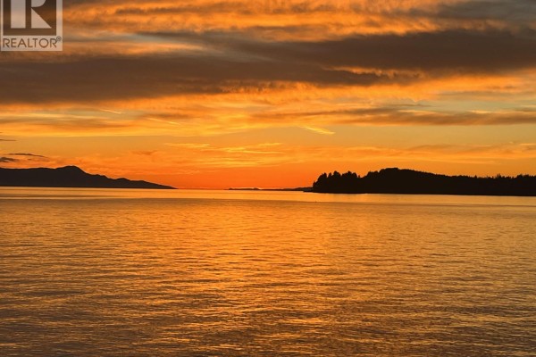 Dramatic orange sunset over the calm ocean with distant tree-covered islands. - 11579 Sunshine Coast Highway, Halfmoon Bay
