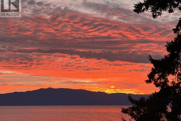 Vibrant red and orange sunset sky with silhouetted mountains and trees by the water. - 11579 Sunshine Coast Highway, Halfmoon Bay
