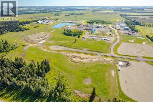 Wide aerial view of the property showing surrounding fields, forests, and distant buildings. - 116, 32532 Range Road 42, Rural Mountain View County