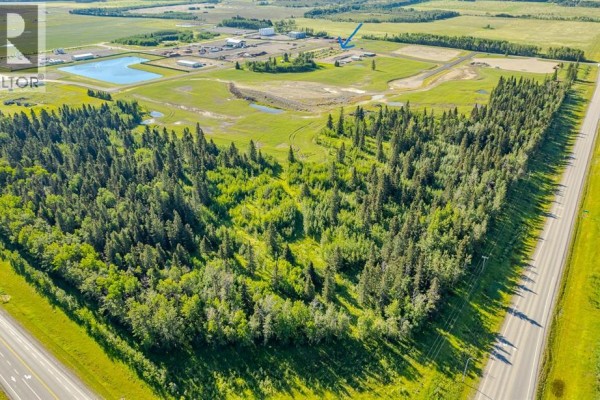 Aerial view of a property bordered by trees on one side and a highway on the other. - 116, 32532 Range Road 42, Rural Mountain View County
