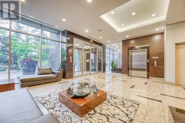 Building lobby with marble floors, glass elevators, modern seating, and a glass coffee table. - 116 - 181 Village Green Square, Toronto