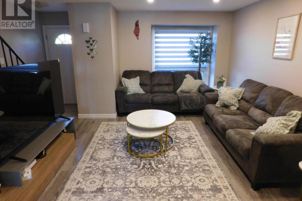 Living room with two dark brown sofas, a patterned rug, and a coffee table. - 116 - 70 Fiddlers Green Road, London North
