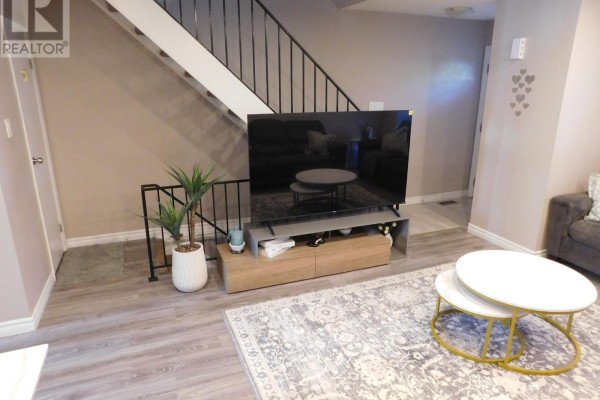 Living room with a large television on a media console and a black metal railing. - 116 - 70 Fiddlers Green Road, London North