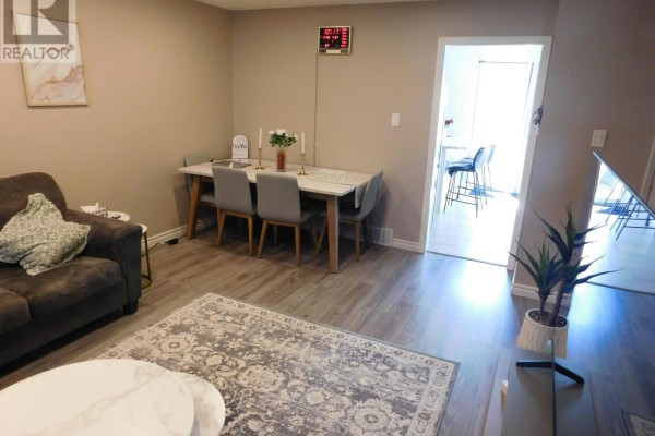 Dining area with a white table and grey chairs adjacent to the living room. - 116 - 70 Fiddlers Green Road, London North