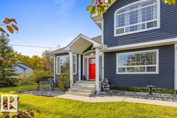 Close-up view of the blue siding house entrance with a red door and covered porch. - #116 53319 Rge Road 14, Rural Parkland County