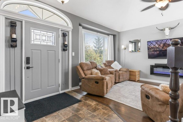 Interior view of the living room with brown recliners, grey door, and electric fireplace. - #116 53319 Rge Road 14, Rural Parkland County