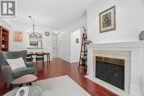 Living room features a marble fireplace, sectional sofa, armchair, and access to an outdoor patio. - 116 5835 Hampton Place, Vancouver