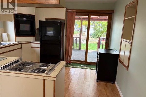 Kitchen with a sliding glass door leading to a backyard patio, light wood cabinets, and light green walls. - 116 5th Avenue E, Gravelbourg