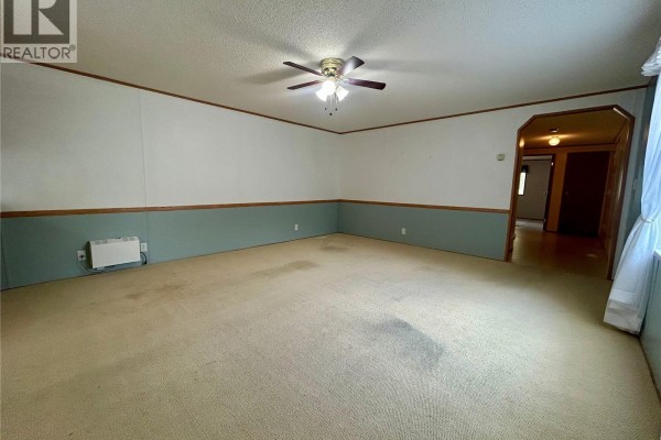 Living room with beige carpet, light blue accent wall, and a heater on the wall. - 116 6th Street, Milestone
