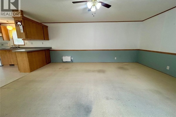 Open concept living area with kitchen cabinets, a sink, and beige carpeting. - 116 6th Street, Milestone