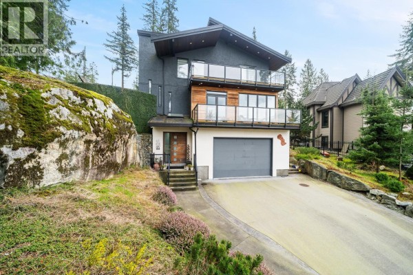 Exterior view of a modern house with dark grey and wood siding, large windows, and balconies. - 116 Deerview Lane, Anmore