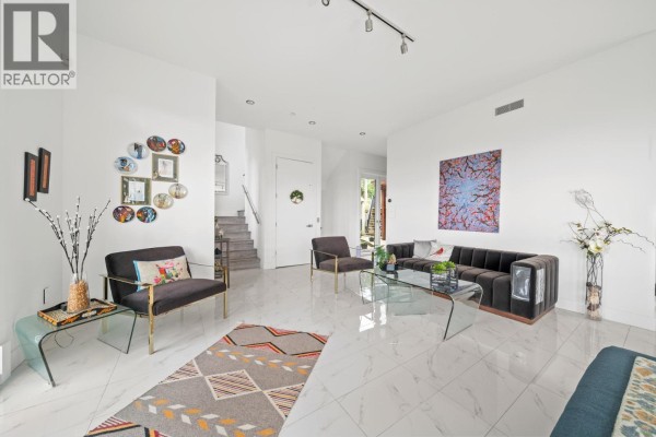 Open-concept living and dining area with large windows, modern furniture, and a view of trees. - 116 Deerview Lane, Anmore