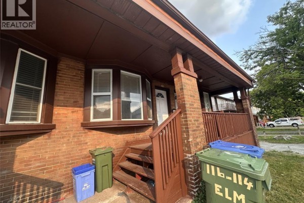 Close-up of a red brick duplex entrance with a white door and wooden porch. - 116 Elm Avenue, Windsor