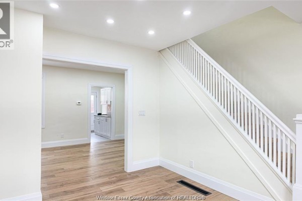 View of a hallway with a white staircase, doorway to kitchen, and light walls. - 116 Elm Avenue, Windsor