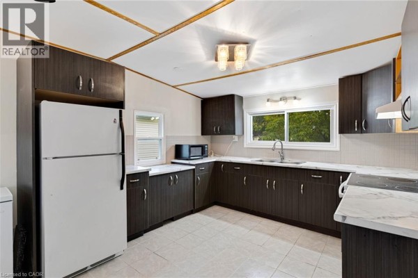 Kitchen with dark brown cabinets, white appliances, and a window with a green view. - 116 Franciscus Street, Waterloo