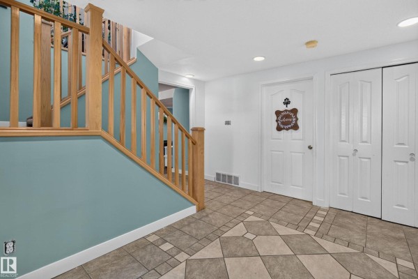 Foyer showing a white door, double closets, a wooden staircase, and patterned tiled flooring. - 116 Lakeshore Drive, Rural Lac Ste  Anne County