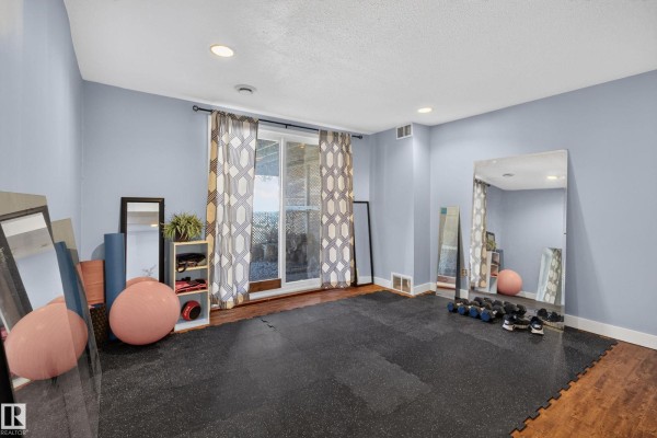 Room with light blue walls, black rubber mat flooring, large mirrors, and workout equipment. - 116 Lakeshore Drive, Rural Lac Ste  Anne County