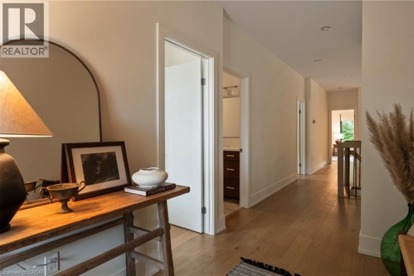 A long, wide hallway with hardwood floors and doors leading to rooms. - 116 Lametti Drive, Fonthill