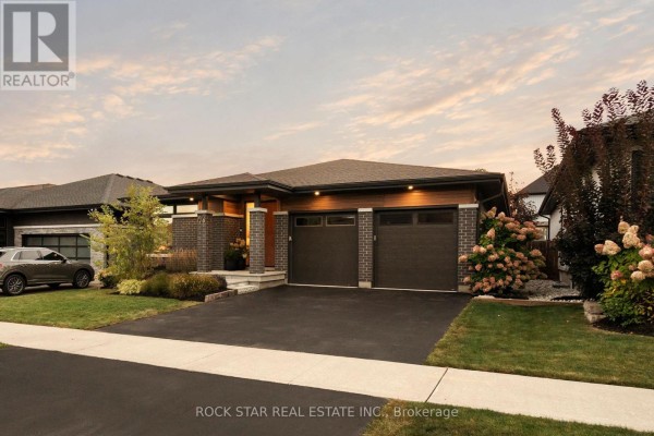 Wide view of modern house exterior with dark brick and wood accents, two-car garage, and landscaped front yard. - 116 Lametti Drive, Pelham