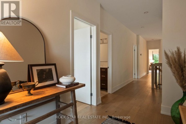 Interior hallway with light wood floors, white doors, a console table with decor, and a large arched mirror. - 116 Lametti Drive, Pelham