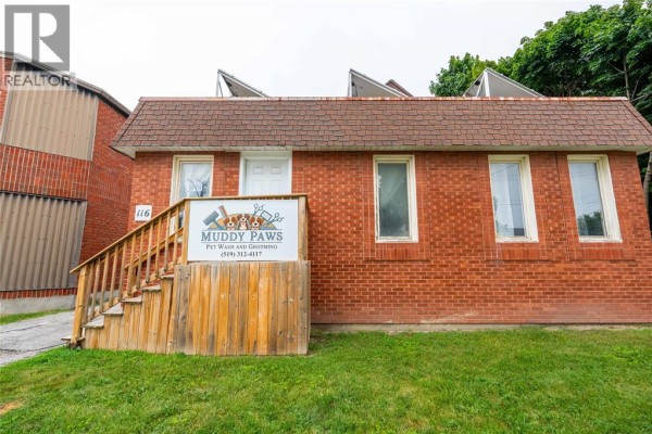 Front exterior of the red brick commercial building with a 'Muddy Paws' sign. - 116 Mitton Street North, Sarnia
