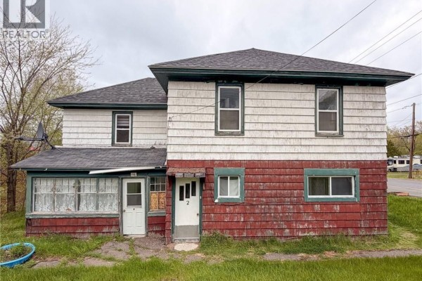 Front exterior of a multi-family house showing two entrances and red lower siding. - 116 Renfrew Street, Dalhousie