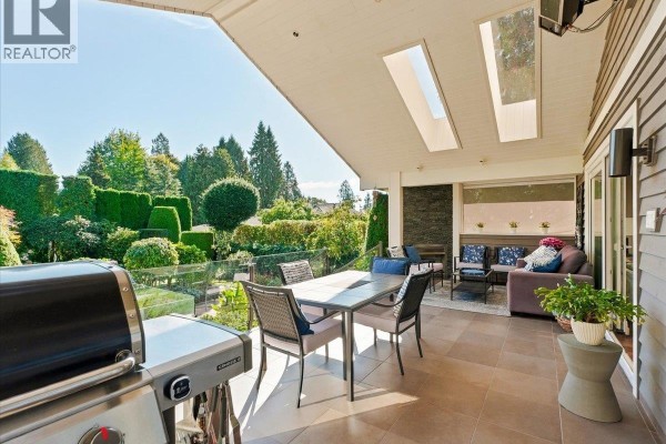 Covered outdoor patio with dining table, chairs, grill, and lounge seating. - 1160 14th Street, West Vancouver