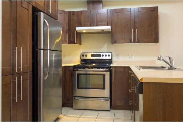 U-shaped kitchen with dark wood cabinets, stainless steel appliances, and light countertops. - 1160 Ch. D'aylmer, #202, Gatineau