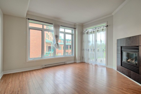 Living room with large windows, a gas fireplace, and wood flooring. - 1160 Ch. D'aylmer, #202, Gatineau