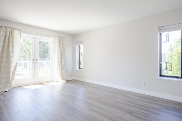 Long hallway with beige walls and tile flooring, leading to other rooms - 11604 75a Avenue, Delta
