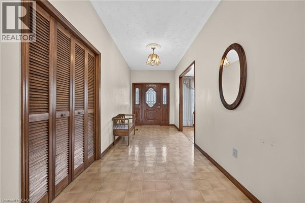 Foyer with wood paneled closet doors, a bench, and a view of the front entrance. - 1163 Greenhill Avenue, Hamilton
