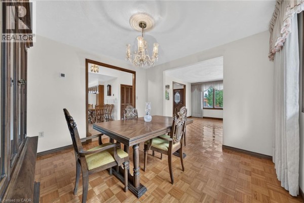Formal dining room with a wooden table, chairs, chandelier, and parquet flooring. - 1163 Greenhill Avenue, Hamilton
