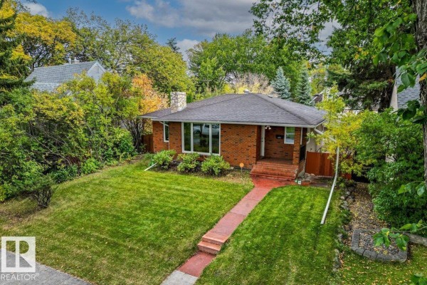Aerial view of a red brick bungalow with a paved walkway and surrounding trees. - 11631 130 St Nw, Edmonton