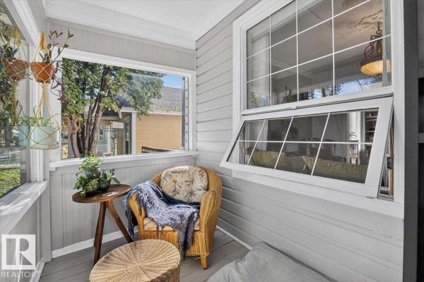 Interior view of the enclosed porch showing wicker seating, a side table, and windows. - 11636 95a St Nw, Edmonton