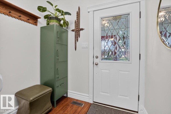 Entryway inside the home, showing a white door with stained glass, a green locker, and a stool. - 11636 95a St Nw, Edmonton