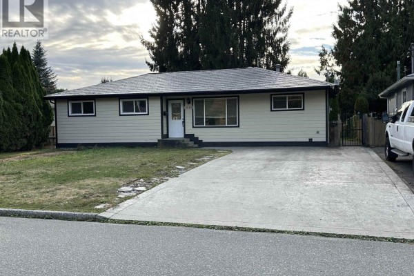 Front exterior of the house with a concrete driveway leading to the garage. - 11645 Steeves Street, Maple Ridge