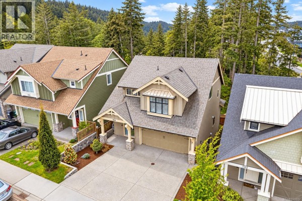 Covered balcony with outdoor seating overlooking a forested backyard with tall trees. - 1166 Bombardier Cres, Langford