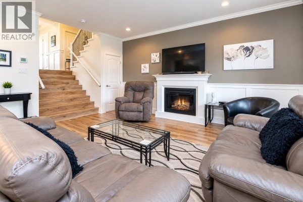 Front exterior of a two-story tan house with a beige garage door and stone accents. - 1166 Bombardier Cres, Langford
