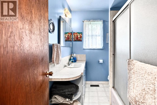 Bathroom with a vanity, sink, mirror, and a glass-enclosed shower. - 11672 Fulton Street, Maple Ridge