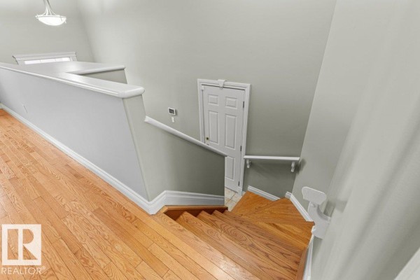 Living area with grey couches, hardwood floors, and light green walls displaying artwork. - 11686 15 Av Nw, Edmonton