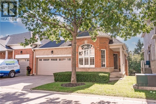 Exterior of a brick townhouse with beige accents, featuring a garage and arched window. - 1169 Dorval Drive Unit# 78, Oakville
